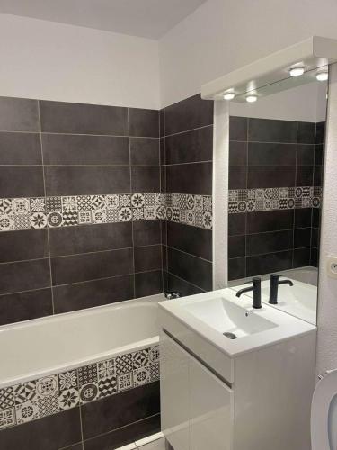 une salle de bains avec lavabo, miroir et baignoire dans l'établissement Agde Studio proche Plage, à Agde