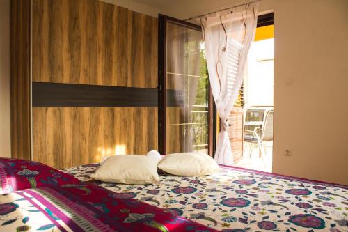 a bedroom with a bed with two pillows and a window at Vasto Apartments in Kaštela