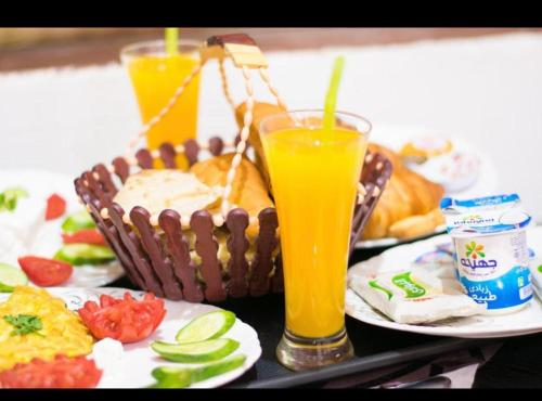 una mesa con una cesta de comida y dos vasos de zumo de naranja en New palace court, en El Cairo