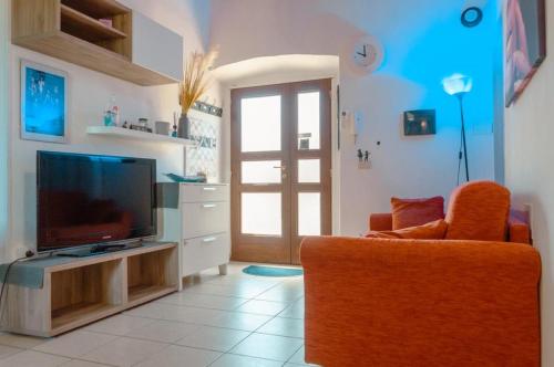 ein Wohnzimmer mit einem TV und einem orangenen Stuhl in der Unterkunft Casa Vacanze Le Cascate in Le Marmore