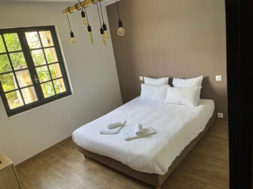 une chambre avec un grand lit blanc avec des serviettes dessus dans l'établissement Maison à Vézac 24220, à Vézac