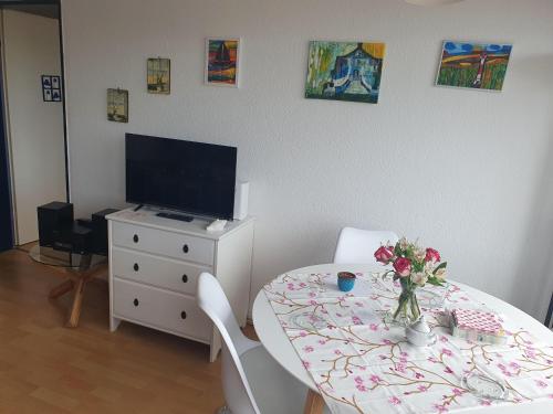 Habitación con mesa, TV, mesa y sillas. en Haus-Crone, en Burgtiefe auf Fehmarn 