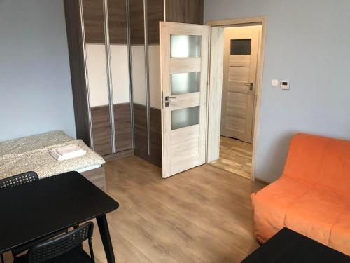 a small room with an orange couch and a door at Apartament Zwirki i Wigury 38 in Bydgoszcz