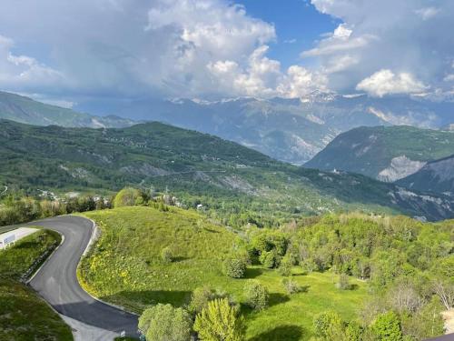a winding road on a hill with mountains in the background at Studio au pied des pistes in Villarembert
