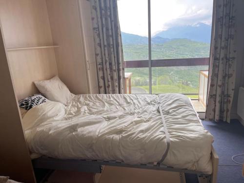 a bed in a room with a large window at Studio au pied des pistes in Villarembert