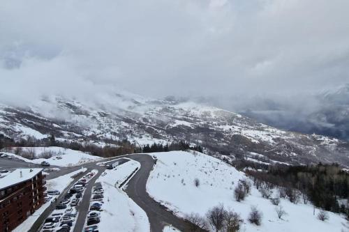 a snow covered mountain with cars on a road at Studio au pied des pistes in Villarembert