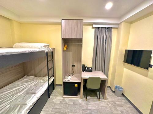 a small room with a desk and a bed at Nona Hotel, Bangkok in Makkasan