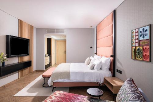 a hotel room with a bed and a flat screen tv at Almond Hotel - Adults only in Neve Ilan