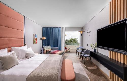a hotel room with a bed and a flat screen tv at Almond Hotel - Adults only in Neve Ilan