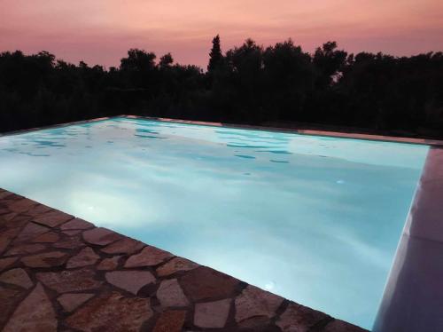 una piscina de agua azul al atardecer en Kalliope Apartments, en Tsoukaladhes