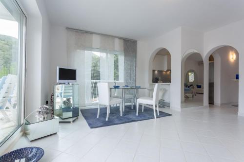 a white living room with a table and chairs at Villa AMICA in Zaton