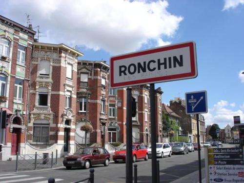 a red and white sign on a street with buildings at Grande chambre + chambre d'appoint in Ronchin