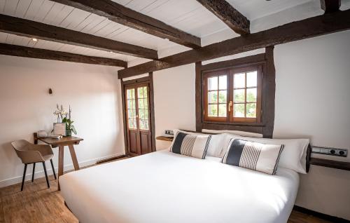 Un dormitorio con una gran cama blanca y una mesa en Casa Rural Arotzenea, en Hondarribia