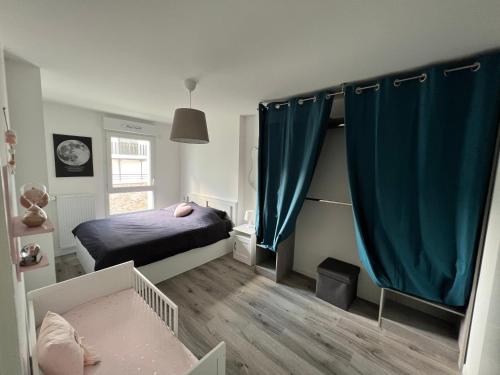 1 dormitorio pequeño con 1 cama y cortinas azules en Appartement avec son jardin d’hiver en Poissy