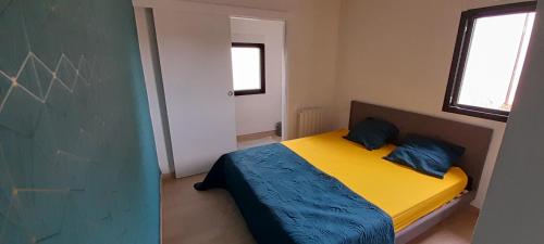 sypialnia z żółtym łóżkiem z niebieską pościelą i 2 poduszkami w obiekcie Maison à L' arcouest proche embarcadere Bréhat w mieście Ploubazlanec