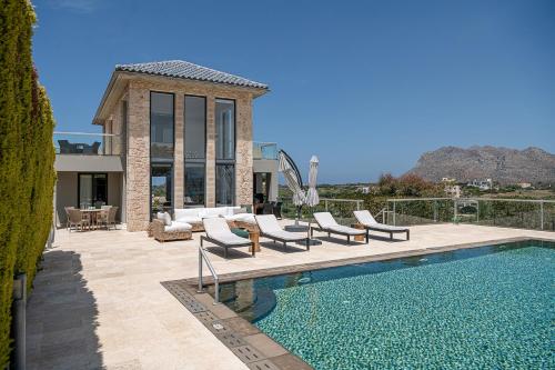 a house with a swimming pool with chairs and a house at Seacrete villas in Chania Town