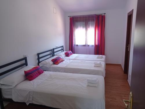 two beds in a hotel room with red curtains at La Via Verde in Miguel-Ibáñez