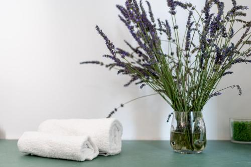 a vase of lavender sitting on a table with towels at Oliva Apartment in Imperia
