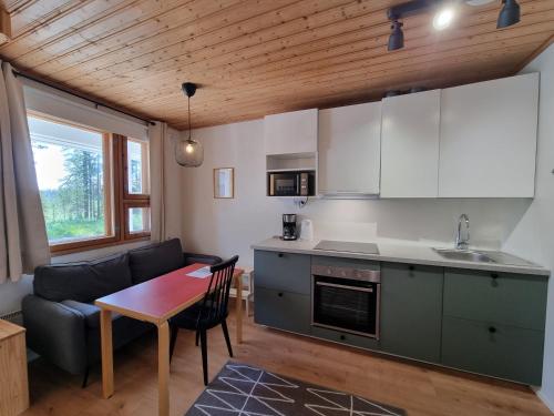 uma cozinha e sala de estar com uma mesa e um sofá em Ylläksen Metsäpirtti - Ulkoilijan koti em Äkäslompolo