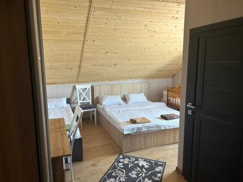1 Schlafzimmer mit 2 Betten und Holzdecke in der Unterkunft Готель Максим Ресторан in Drogovyzhe