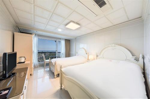 Donghae Medical Spa Convention Hotel في دونغ هاي: غرفه فندقيه سريرين وتلفزيون