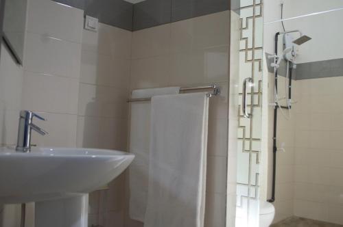 a white bathroom with a sink and a shower at Paramount Residence 5 in Peliyagoda