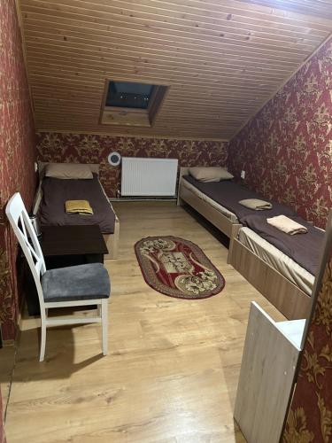 a room with two beds and a table and a chair at Готель Максим Ресторан in Drogovyzhe