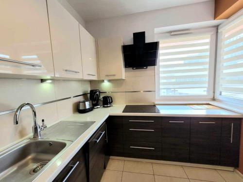 クラクフにあるApartament Dark Chocolate 4 persons Down Townの白いキャビネット、シンク、窓付きのキッチン