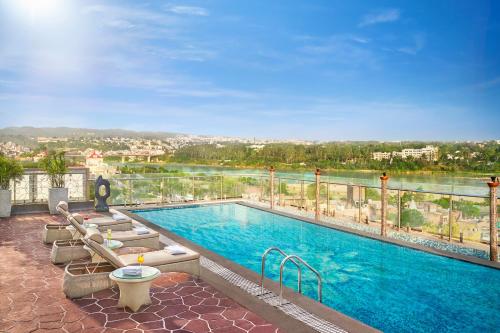 a swimming pool with chairs and a view of a river at Vivanta Jammu City Centre in Jammu
