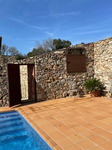 a stone wall and a swimming pool next to a building at Can Clarós in Capmany