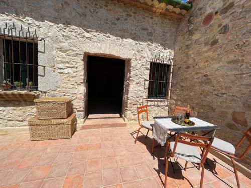 a patio with a table and chairs in a stone building at Can Clarós in Capmany
