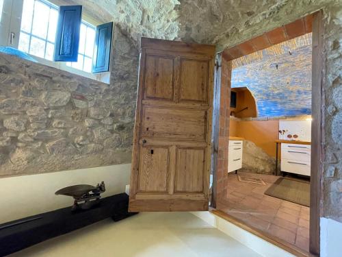 a kitchen with a wooden door and a stone wall at Can Clarós in Capmany