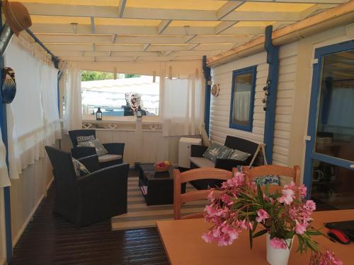 a porch with chairs and a table with flowers on it at Le Paradis Bleu camping les pins maritimes in Hyères