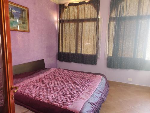 a bedroom with a bed with pink walls and windows at Keur Magatte in Saint-Louis