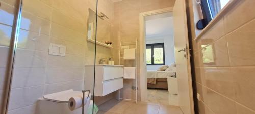 a bathroom with a shower and a toilet and a bedroom at Apartmani Mariosa in Vrbnik
