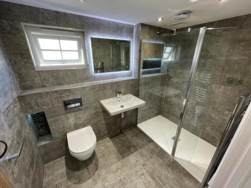a bathroom with a shower and a toilet and a sink at Sunnyside Cow Shed one bedroom central Cornwall in Truro