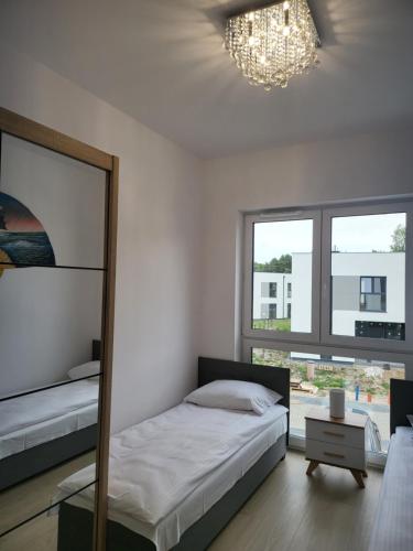 - une chambre avec un lit, un miroir et un lustre dans l'établissement Bursztynek - Luxoro Park, à Ustka