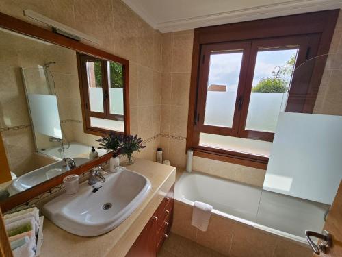 y baño con lavabo, bañera, lavabo y espejo. en Vistas magnificas Islas Atlanticas, en Baiona