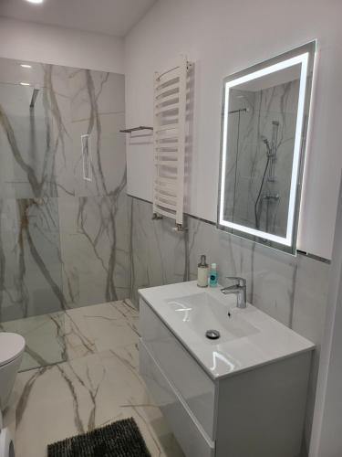 une salle de bain blanche avec un lavabo et un miroir dans l'établissement Bursztynek - Luxoro Park, à Ustka
