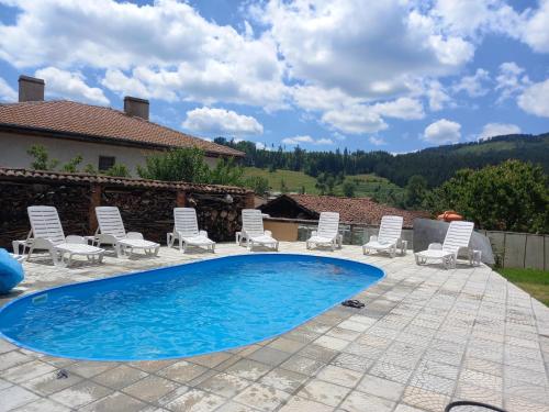 eine Terrasse mit Stühlen und einem Swimmingpool in der Unterkunft Kъща за гости Демария in Kopriwschtiza