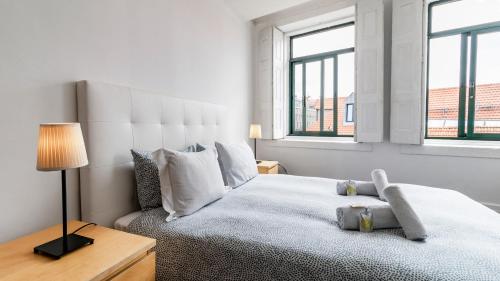 a white bedroom with a large bed and two windows at Onefam Clerigos in Porto