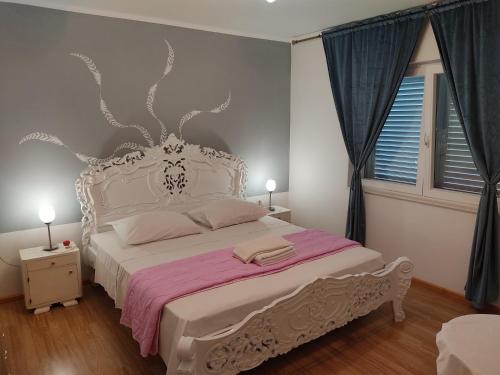 een slaapkamer met een wit bed en een roze deken bij Apartments Milka in Vodice