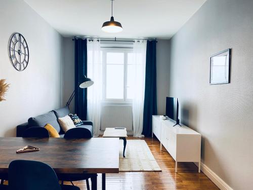 a living room with a table and a couch and a television at Sweet Cēmoi Retreat au calme, proche gare, Netflix in Grenoble
