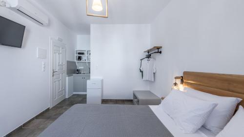 a white bedroom with a bed and a television at Michalis Studios in Pollonia
