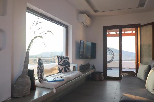 a living room with a couch and a large window at Villa Ktima Lipsi - Jacuzzi & Stunning Sea Sunsets in Klouvas