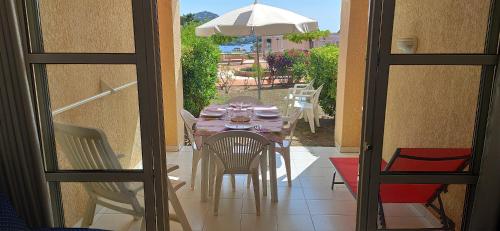 une table avec des chaises et un parasol sur une terrasse dans l'établissement Agay Cap Esterel, le village Belvédère T2 climatisé Rez-de-Jardin, Vue Mer, Piscine et Parking inclus, à Agay