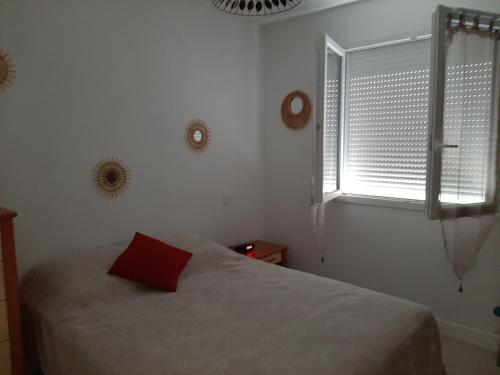 - une chambre avec un lit doté d'un oreiller rouge et d'une fenêtre dans l'établissement Petite maison de campagne, à Calamane