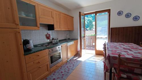 a kitchen with wooden cabinets and a door to a patio at Casa Natalie in Pinzolo