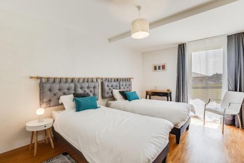 a bedroom with two beds and a window at Blonay Garden Apartment - Swiss Hotel Apartments in Blonay