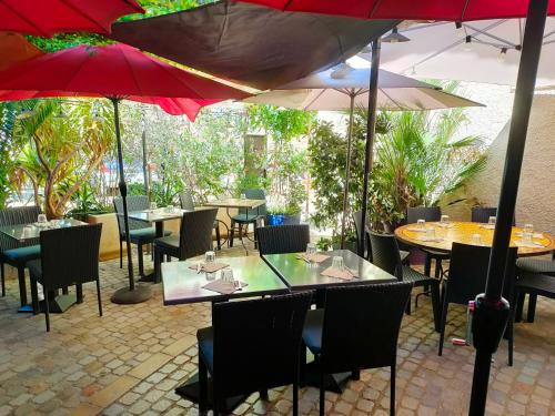 un ristorante con tavoli, sedie e ombrelloni di Au Remp'Arts a Elne